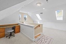 carpeted office space with vaulted ceiling with skylight