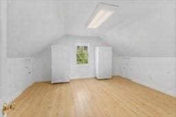 additional living space featuring light wood-style floors and vaulted ceiling