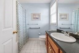 bathroom featuring baseboards, a shower with shower curtain, toilet, tile patterned floors, and vanity