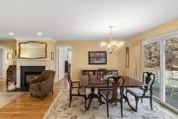 dining area with a fireplace, an inviting chandelier, and wood finished floors