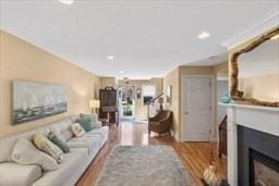 living room featuring recessed lighting, wood finished floors, and a glass covered fireplace