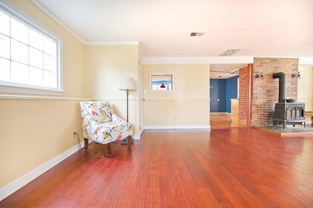 38 Kimball Beach Rd, Hingham, MA 02043 - living area with wood-type flooring, plenty of natural light, a wood stove, baseboards, and ornamental molding
