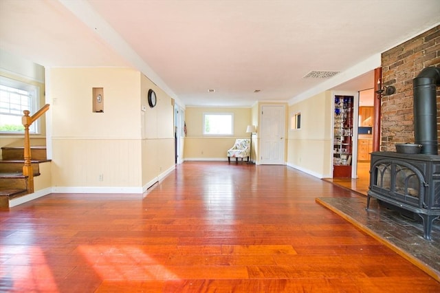 38 Kimball Beach Rd, Hingham, MA 02043 - unfurnished living room featuring a wood stove, hardwood / wood-style flooring, stairway, a wainscoted wall, and baseboards