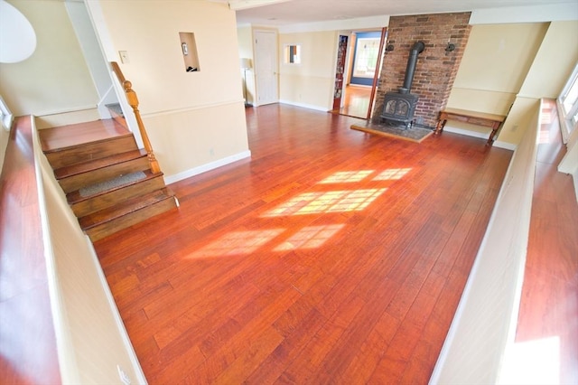 38 Kimball Beach Rd, Hingham, MA 02043 - unfurnished living room featuring a wood stove, wood finished floors, stairway, and healthy amount of natural light