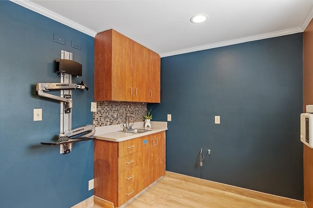 kitchen featuring tasteful backsplash, ornamental molding, a sink, and brown cabinets