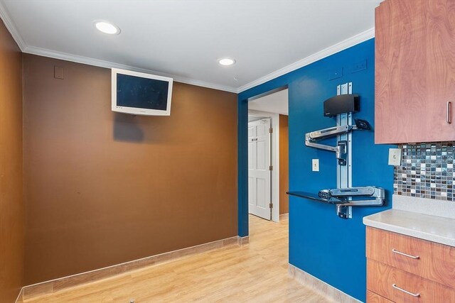 kitchen featuring brown cabinets, crown molding, tasteful backsplash, light countertops, and light wood-style floors