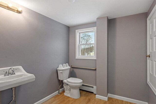 bathroom featuring toilet, a baseboard radiator, baseboards, and wood finished floors