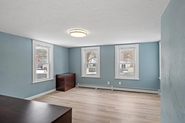 interior space featuring a baseboard radiator, baseboards, a textured ceiling, and wood finished floors