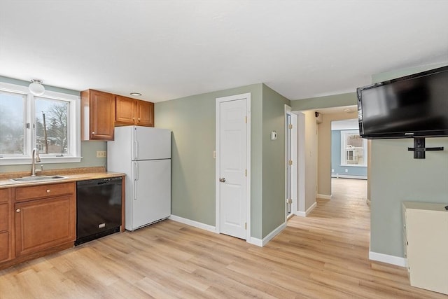 kitchen with brown cabinets, light wood-style floors, freestanding refrigerator, a sink, and dishwasher
