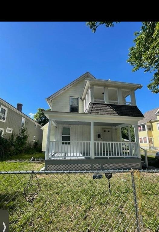 view of front facade with a front yard, fence, and covered porch