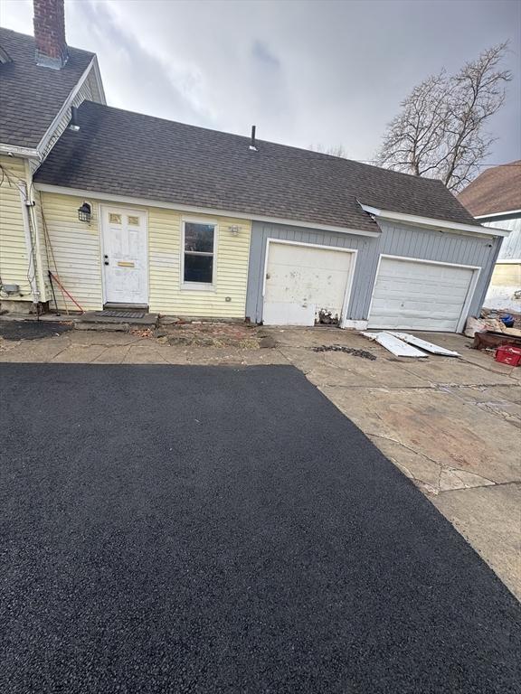 view of front of home featuring aphalt driveway, roof with shingles, and an attached garage