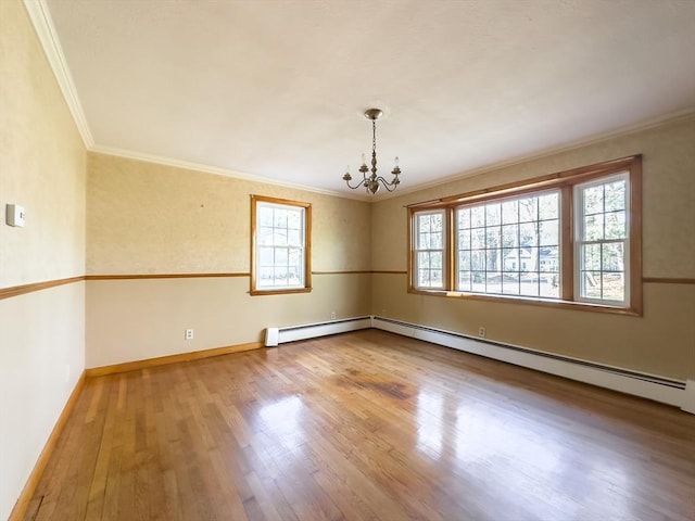 spare room with a wealth of natural light, crown molding, an inviting chandelier, and hardwood / wood-style flooring