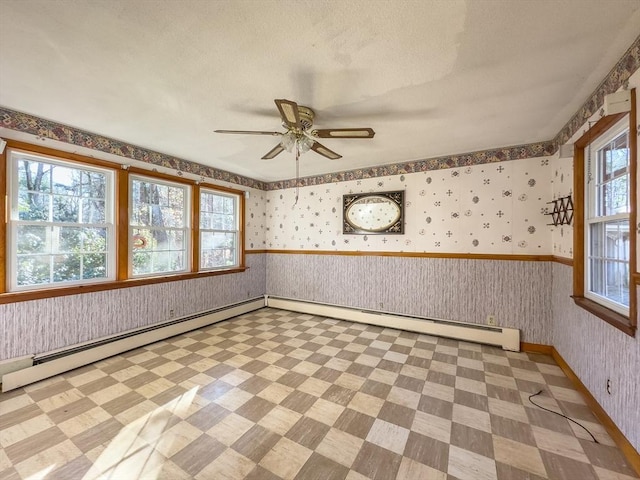 unfurnished room featuring plenty of natural light, ceiling fan, a textured ceiling, and a baseboard heating unit