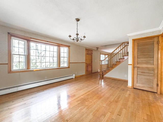 unfurnished living room featuring baseboard heating, a chandelier, a textured ceiling, light wood-type flooring, and ornamental molding