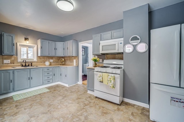 kitchen with tasteful backsplash, light countertops, a sink, white appliances, and baseboards