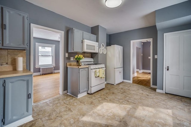 kitchen with white appliances, baseboards, light countertops, decorative backsplash, and radiator