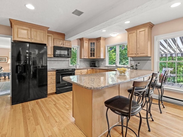 71 Nourse St, Westborough, MA 01581 - kitchen featuring black appliances, light wood finished floors, a peninsula, light stone counters, and decorative backsplash