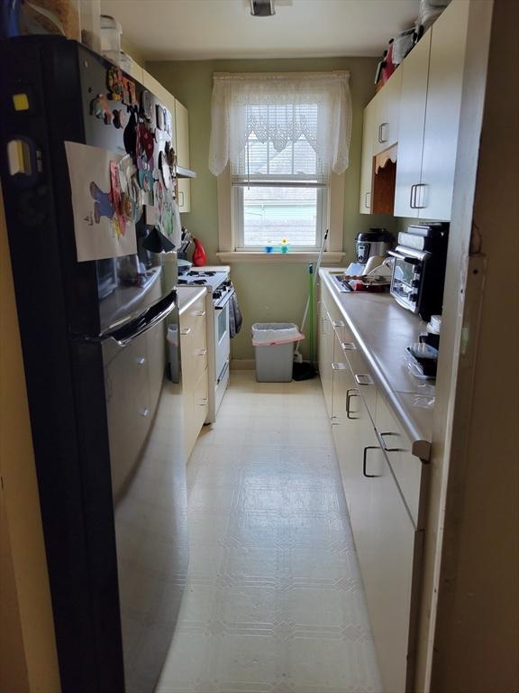 314-316 Dartmouth St, New Bedford, MA 02740 - kitchen with freestanding refrigerator, white gas stove, white cabinets, and light countertops