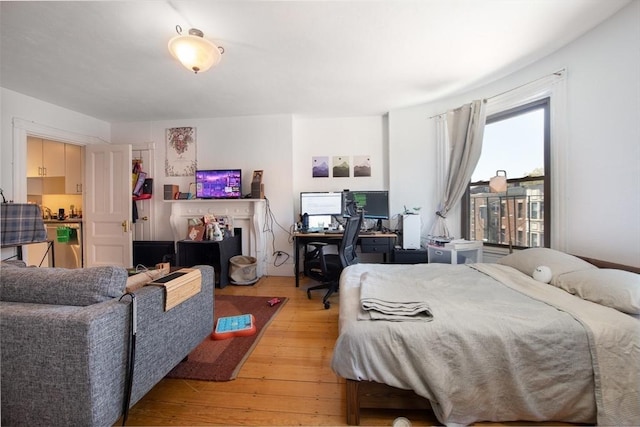 bedroom featuring light wood-type flooring and an office area
