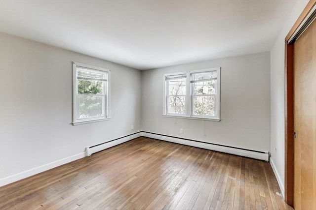 unfurnished room with a baseboard radiator, wood-type flooring, and baseboards