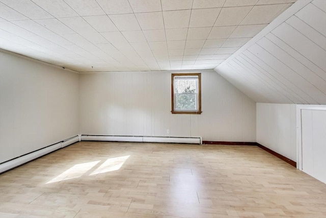 additional living space with lofted ceiling, a baseboard heating unit, and wood finished floors