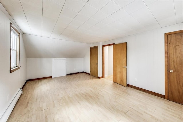 bonus room featuring light wood-type flooring, baseboards, a baseboard heating unit, and lofted ceiling