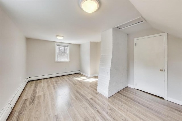 unfurnished room with a baseboard heating unit, light wood finished floors, and baseboards