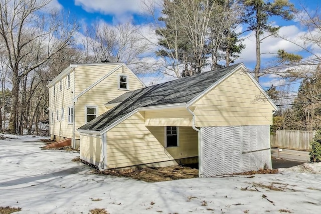 view of side of home with a shingled roof and fence