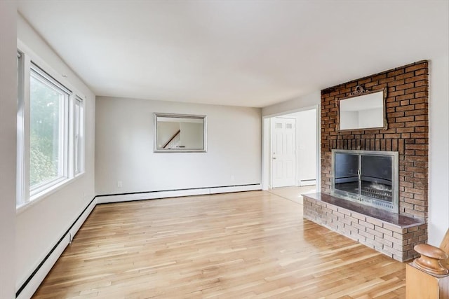 unfurnished living room with wood finished floors, a baseboard radiator, and a fireplace