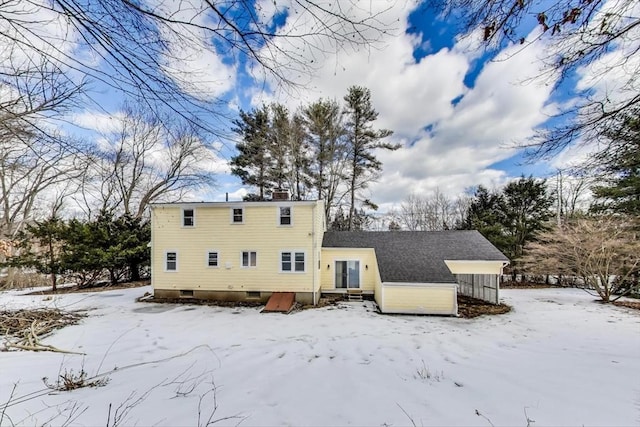 snow covered back of property with a chimney