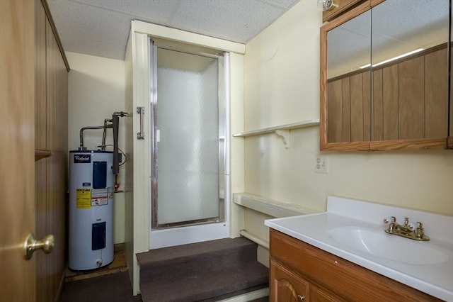 full bath with a paneled ceiling, vanity, a stall shower, and water heater