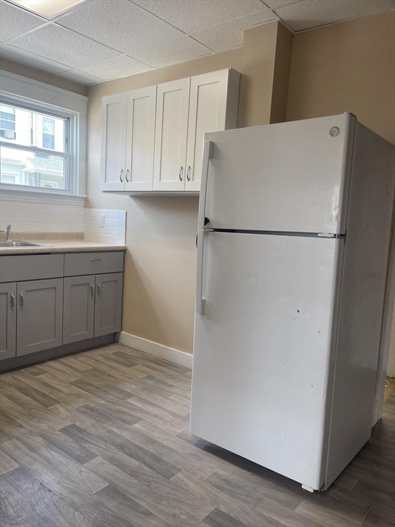466-470 Cambridge St, Fall River, MA 02721 - kitchen with freestanding refrigerator, gray cabinetry, light wood-style flooring, a drop ceiling, and light countertops