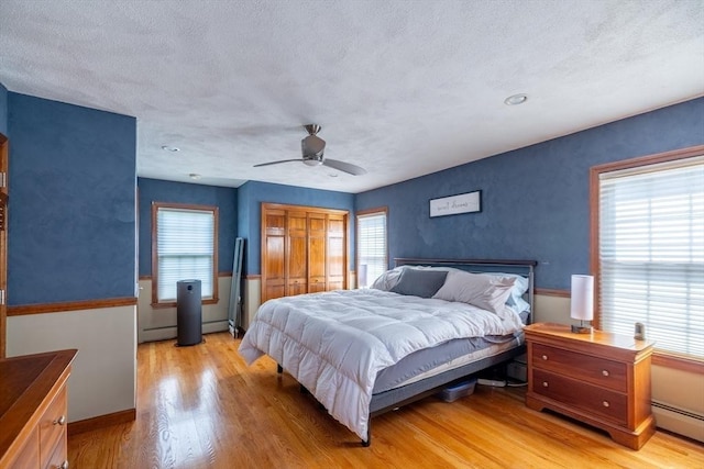 4 Fall St, Malden, MA 02148 - bedroom featuring baseboard heating, light wood-style flooring, multiple windows, a textured ceiling, and a baseboard heating unit
