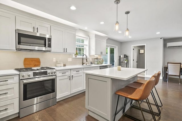 116 Pilgrim Rd Unit 116, Haverhill, MA 01832 - kitchen featuring appliances with stainless steel finishes, a wall mounted AC, backsplash, a breakfast bar, and dark wood-type flooring