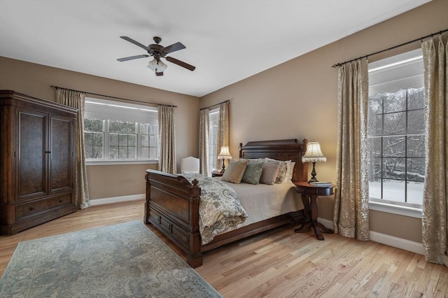 bedroom with multiple windows, ceiling fan, and light hardwood / wood-style floors