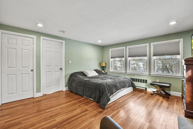 bedroom with radiator heating unit, recessed lighting, wood finished floors, and baseboards