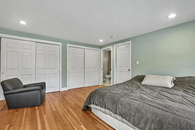 bedroom featuring baseboards, recessed lighting, wood finished floors, and multiple closets