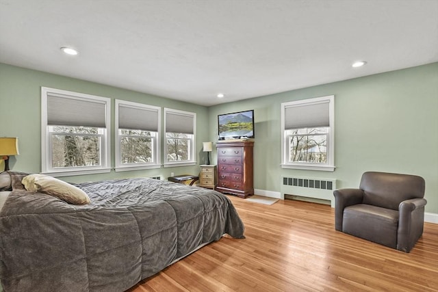 bedroom featuring radiator, light wood-style floors, multiple windows, and recessed lighting