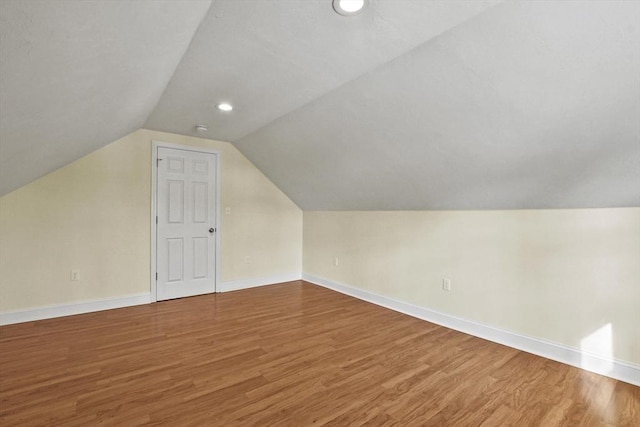 additional living space with recessed lighting, vaulted ceiling, baseboards, and wood finished floors