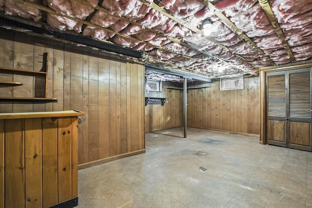 unfinished basement with baseboards, wooden walls, and light floors