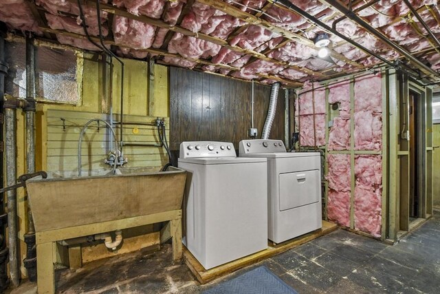 laundry area with washer and dryer, laundry area, a sink, and wooden walls