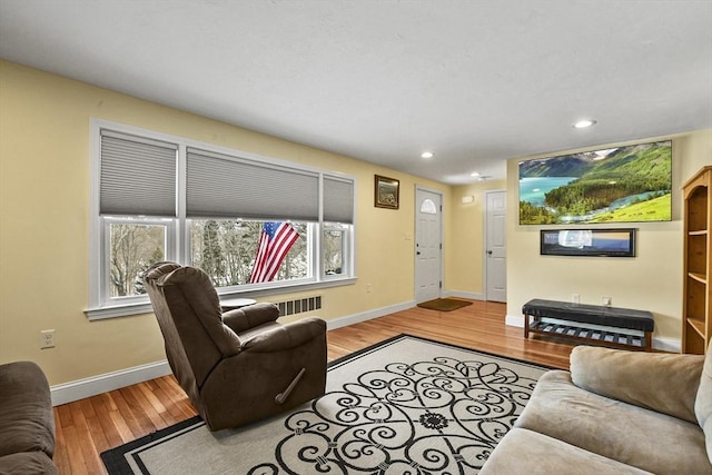 living area featuring baseboards, radiator, recessed lighting, and light wood-style floors