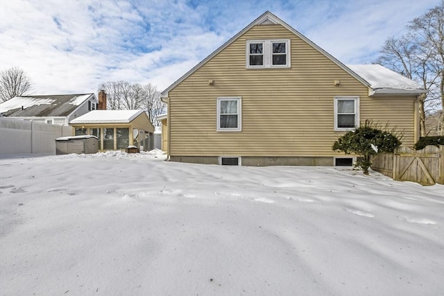 view of snowy exterior with a hot tub and fence