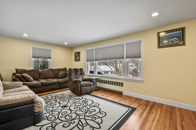 living room with baseboards, light wood-style floors, recessed lighting, and radiator