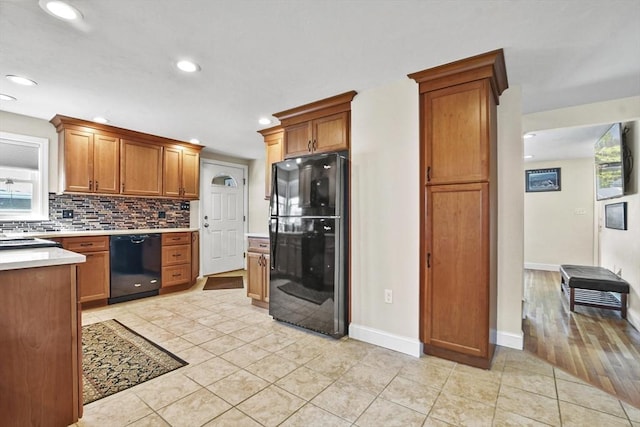 kitchen featuring black appliances, brown cabinetry, light countertops, and backsplash