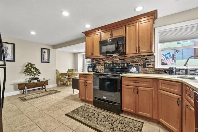 kitchen with black appliances, backsplash, light countertops, and a sink