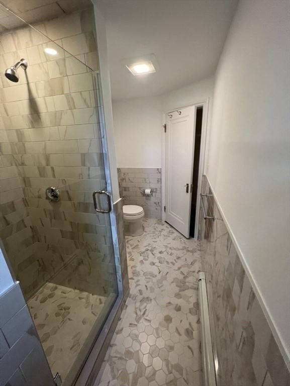 bathroom featuring tile walls, a shower with door, and toilet