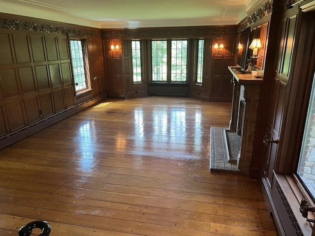 unfurnished living room with a baseboard radiator, radiator heating unit, and light hardwood / wood-style floors