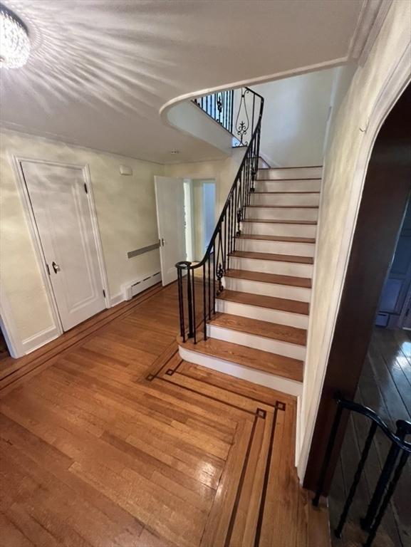 staircase with a baseboard radiator and wood-type flooring