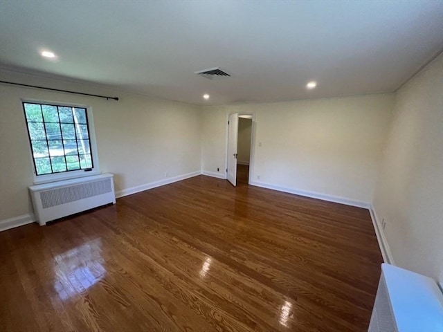 spare room featuring radiator and dark hardwood / wood-style flooring